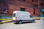 White compact popular cargo mini van for local deliveries and business standing on the warehouse parking lot