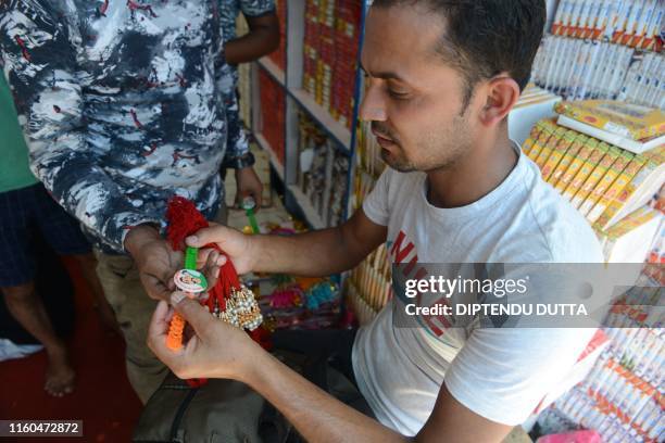 Shopkeeper holds 'rakhis' depicting Indian Air Force Wing Commander Abhinandan Varthaman at a wholesale store ahead of the Hindu festival Raksha...