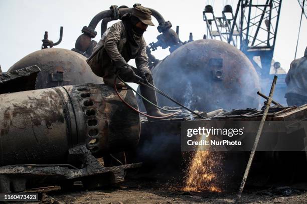 An Indonesian shipyard worker uses a blow torch to break up parts of a ship brought to shore for scrap metal at a ship breaking yard in Jakarta,...