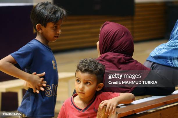 Libyan women and children attend a meeting with charity workers at a gym in the capital Tripoli on August 7 during a gathering of people displaced...