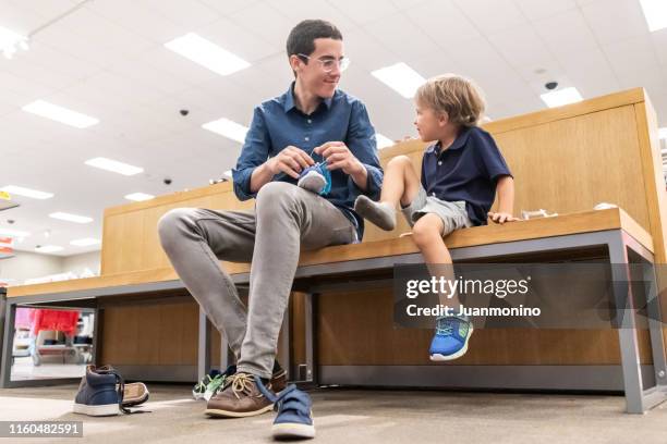 jonge man winkelen voor schoenen voor zijn zoon - schoenenwinkel stockfoto's en -beelden