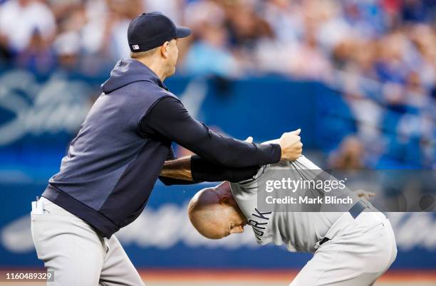 Brett Gardner of the New York Yankees is held back by manager Aaron Boone as he argues with umpires while playing the Toronto Blue Jays in the fourth...