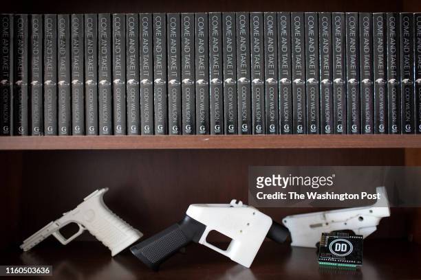 Bookshelf at the Defense Distributed factory displays copies of Cody Wilsons book, 3D-printed guns and parts.