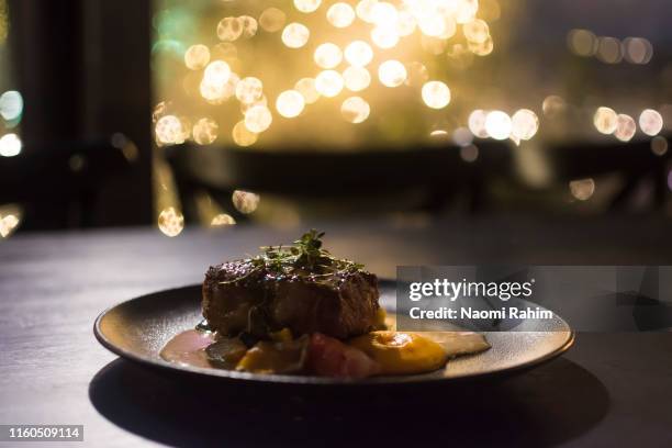 gourmet grilled reindeer entrecote steak, lappish potatoes and sauce, served on a contemporary plate on a dark timber table - portion stock pictures, royalty-free photos & images