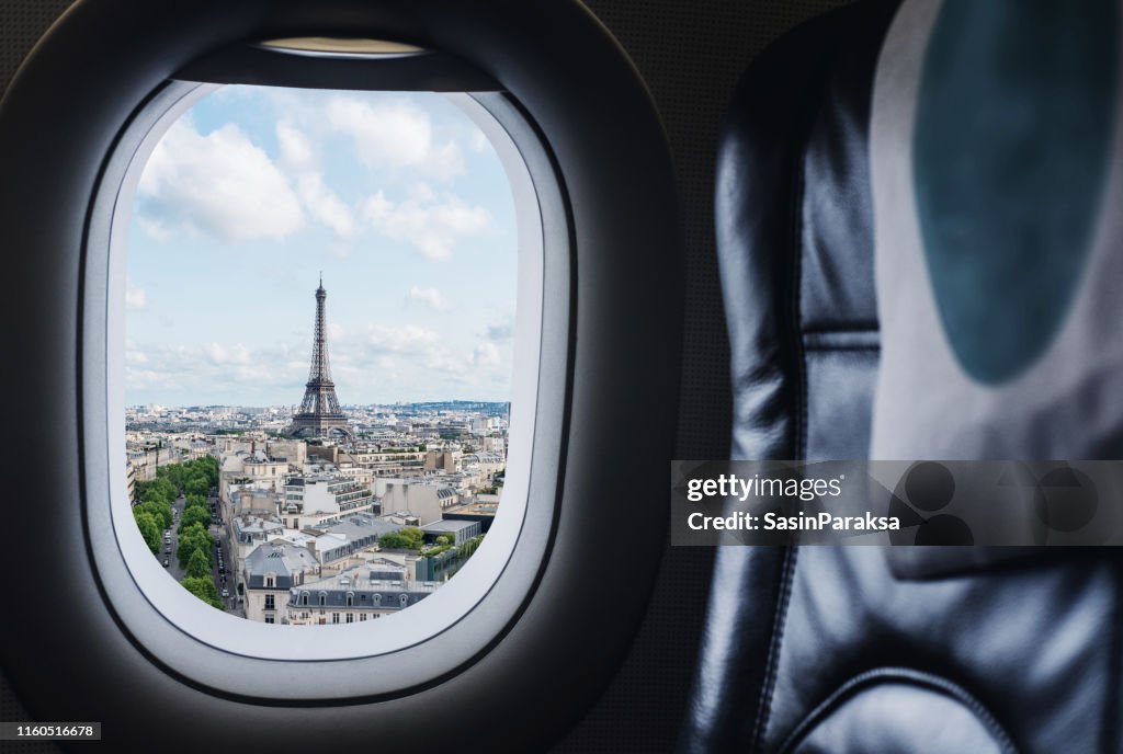 Traveling Paris, France famous landmark and travel destination in Europe. Aerial view Eiffel Tower through airplane window