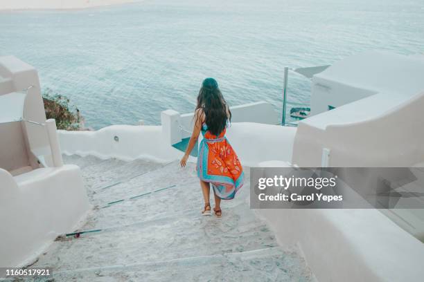 young beautiful woman walking away in santorini,greece - greek style stock pictures, royalty-free photos & images