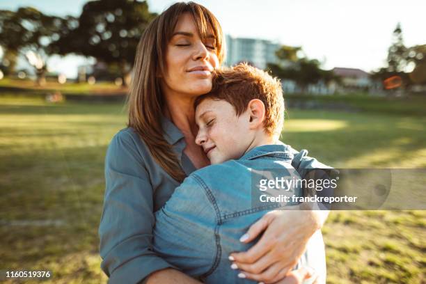 adolescente abbracciato con la mamma consolando suo figlio - figlio maschio foto e immagini stock