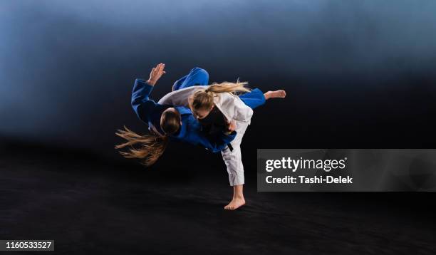 vrouwelijke judoka die haar partner op de grond gooit - judo stockfoto's en -beelden