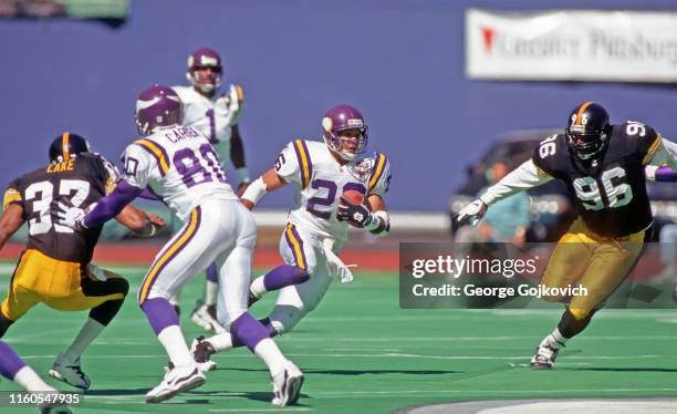 Running back Robert Smith of the Minnesota Vikings runs with football after taking a handoff from quarterback Warren Moon as he is pursued by...