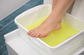 Woman foot treatment in paraffin bath at the spa