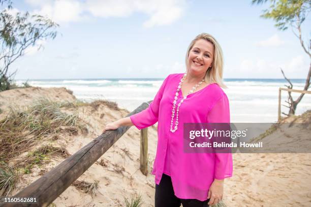 portait of a happy, carefree woman with blonde hair by the beach in a bright pink shirt - thisisaustralia stock-fotos und bilder