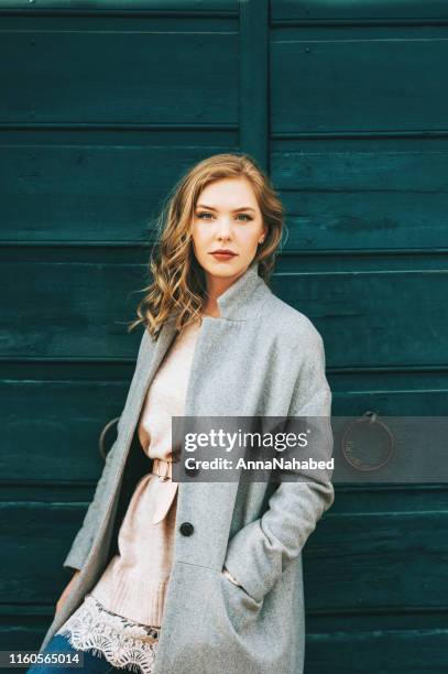 Outdoor portrait of beautiful young woman posing in the street, wearing grey coat
