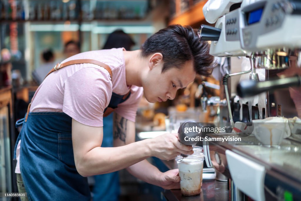 Asian Barista making coffee in the cafe