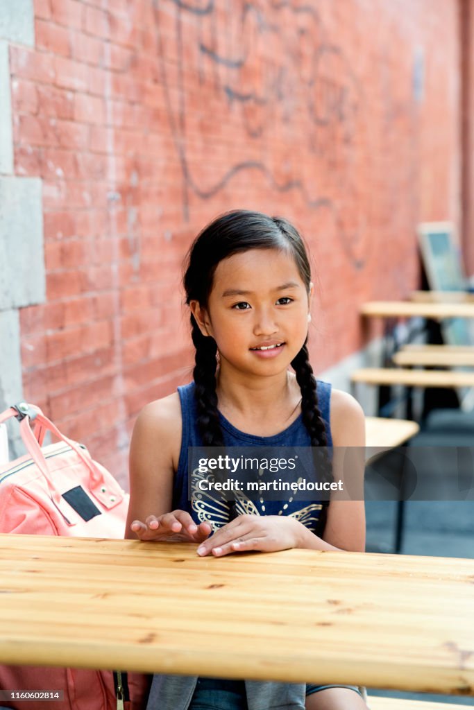 Portrait of preteen girl sitting at a city terrace.