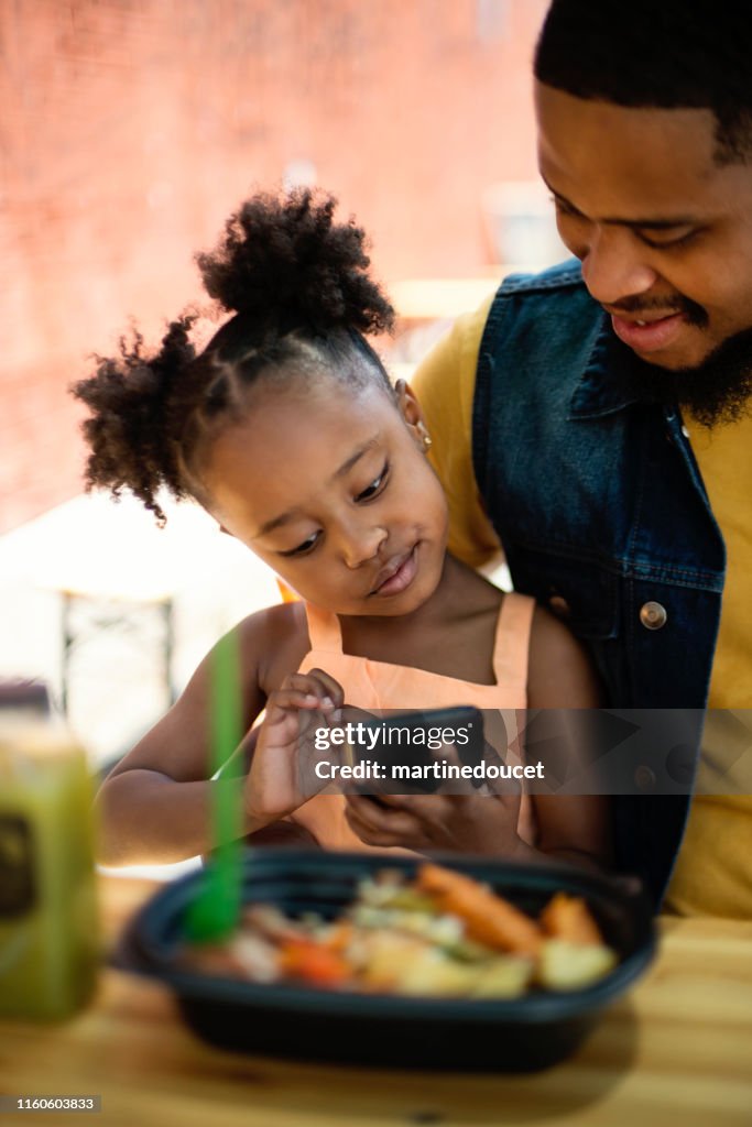 Father and daughter eating take out food outdoors.