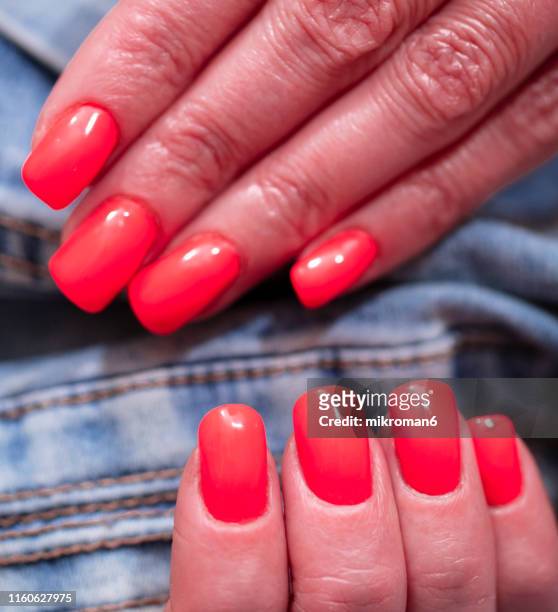 close-up of woman fingers with nail art manicure with neon pink red colour - acrylic painting stock-fotos und bilder