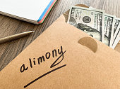Divorce and separation concept. Alimony written on an envelope with dollars.