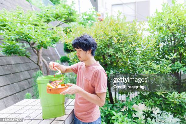 homme mettant des ordures de nourriture dans le composteur - daily bucket photos et images de collection