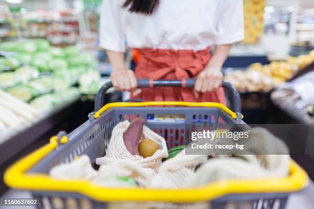 young woman doing shopping at supermarket with her reusable shopping bag - plastic free stock pictures, royalty-free photos & images