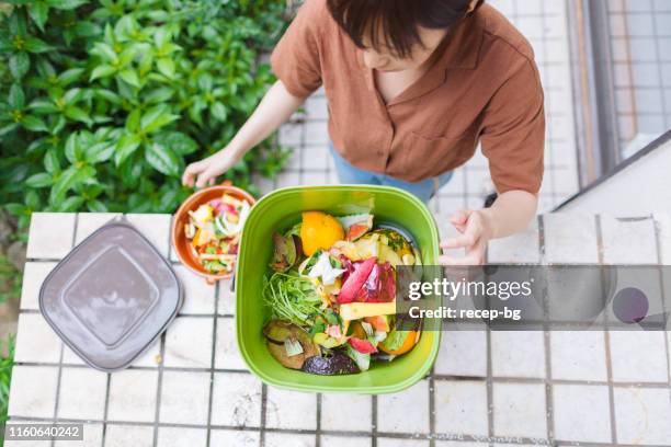 vrouw zetten voedsel vuilnis in compost - compost stockfoto's en -beelden