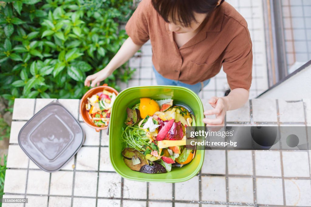 Woman putting food garbage into composter
