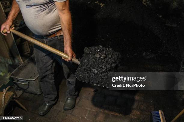 Man adding wet waste anthracite culm coal to a coal-fired central heating furnace in a single-family house in the countryside is seen in Sypniewo,...