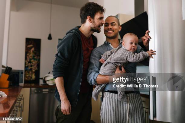 smiling gay men with baby - two parents stock-fotos und bilder
