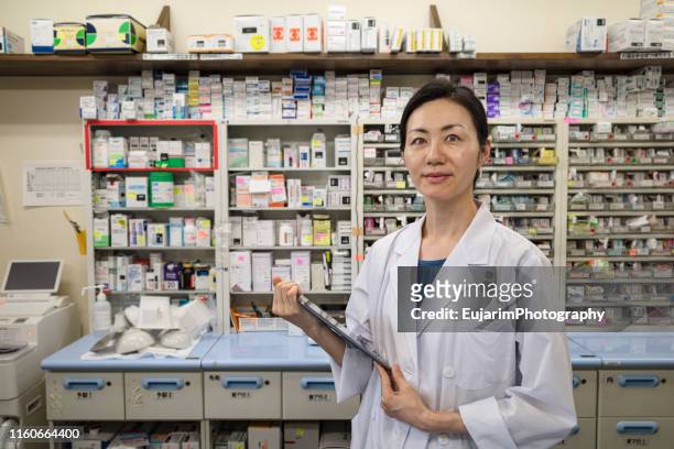 japanese female pharmacist holding digital tablet in a drugstore - female pharmacist with a digital tablet imagens e fotografias de stock