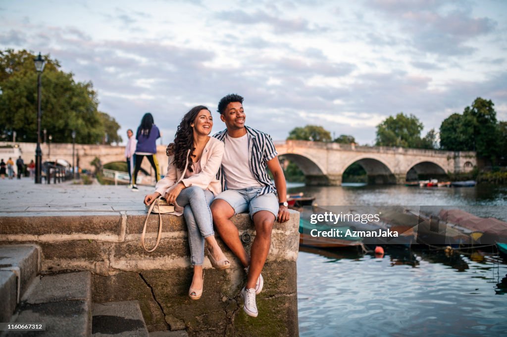 Smiling Couple Sitting on Embankment in Richmond Upon Thames