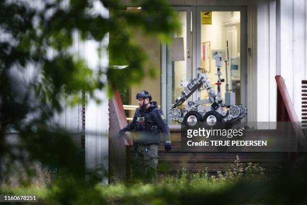 Norwegian police expert walks past a robot in front of the al-Noor islamic center mosque where a gunman, armed with multiple weapons, went on a...