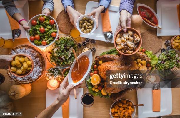 above view of passing food during thanksgiving dinner. - thanksgiving food stock pictures, royalty-free photos & images