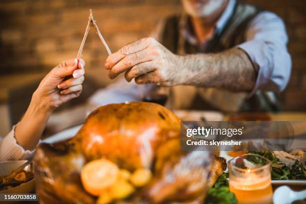 感謝祭のディナーにウィッシュボーンを引っ張る認識できない人々のクローズアップ。 - wishbone ストックフォトと画像