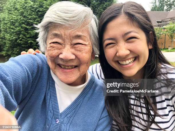 grandmother in 90s taking selfie with granddaughter outside retirement home - asian grandmother stock pictures, royalty-free photos & images