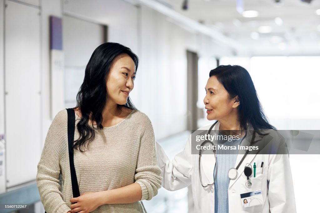 Smiling mature doctor talking to woman in hospital