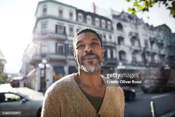 portrait of smiling man in the city - city street stock-fotos und bilder