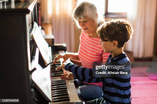 senior grandmother teaching her grandson to play the piano - teach muziekinstrument stockfoto's en -beelden