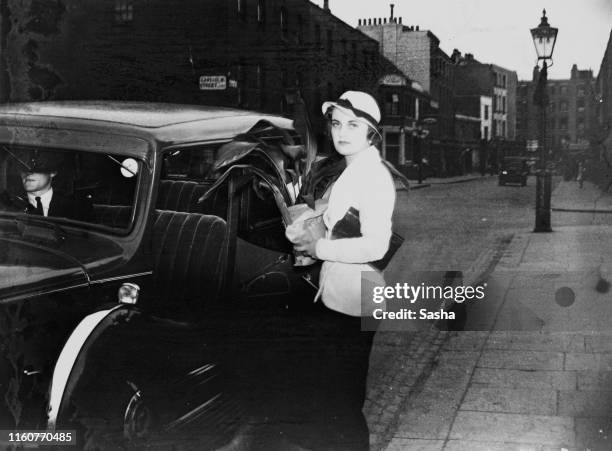 English socialite Margaret Whigham holding a pot plant as she prepares to get into a chauffeur-driven car, London, June 1930.