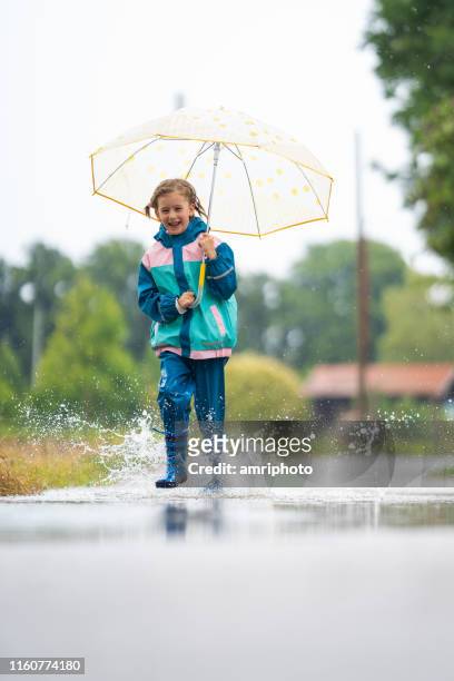 school girl having fun in rain - kagoul stock pictures, royalty-free photos & images