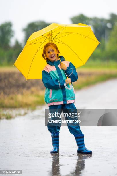 6 year old girl in rain clothes with umbrella smiling at camera - kagoul stock pictures, royalty-free photos & images