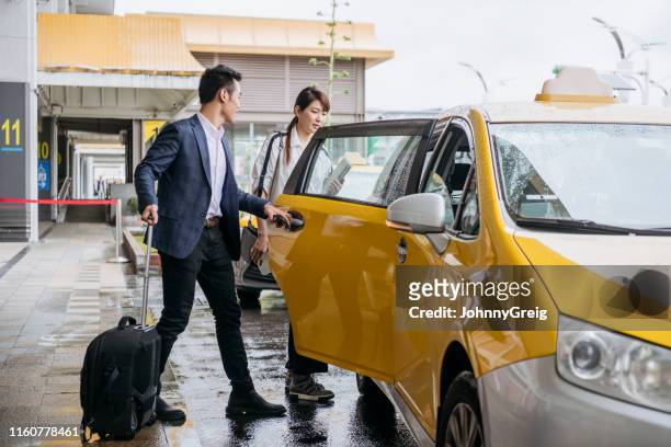 businessman opening cab door for woman outside airport - taxi stock pictures, royalty-free photos & images