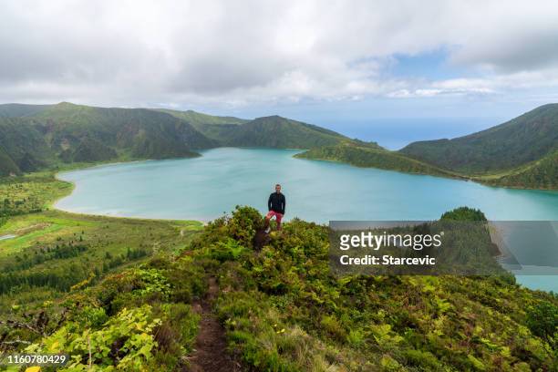 young man hiking with epic lake background - azores people stock pictures, royalty-free photos & images