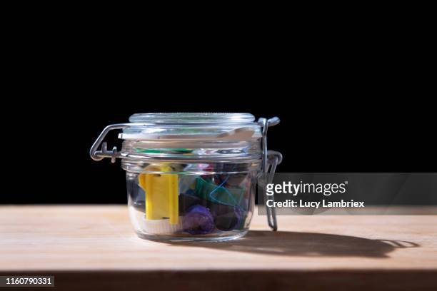 plastic waste 'preserved' in a small mason jar - filling jar stock pictures, royalty-free photos & images