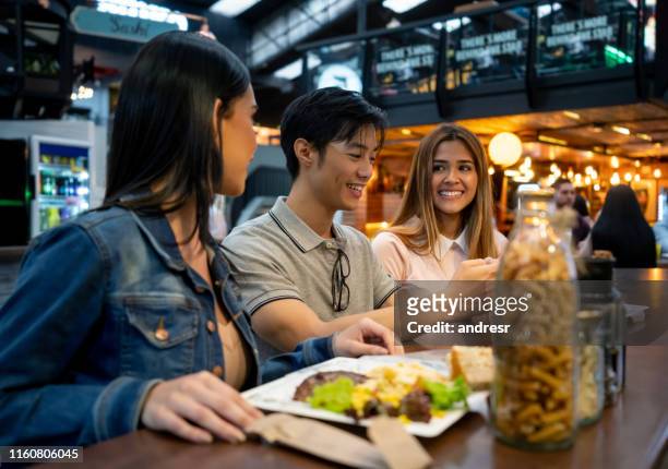 gruppo felice di persone che mangiano alla food court - man eating at diner counter foto e immagini stock