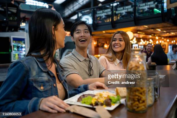 gruppo di amici che mangiano insieme in un ristorante - man eating at diner counter foto e immagini stock