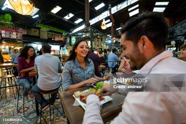 happy couple eating at the food court - food court stock pictures, royalty-free photos & images