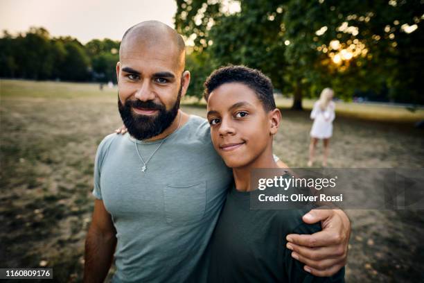 portrait of smiling father with son in a park - green tee stock pictures, royalty-free photos & images