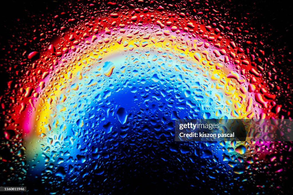 Waterdrops on window glass with colorful abstract background .