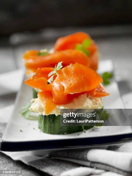 gurkenkanape mit geräuchertem lachs und geröstetem knoblauch hummus - räucherlachs stock-fotos und bilder