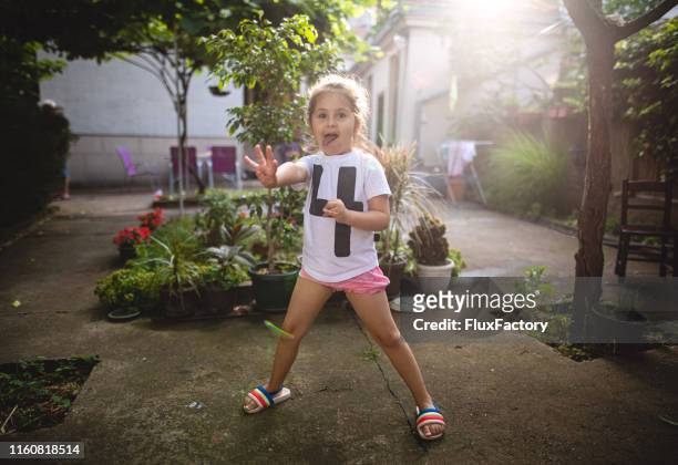 little girl making faces while playing in her yard - one in four people stock pictures, royalty-free photos & images