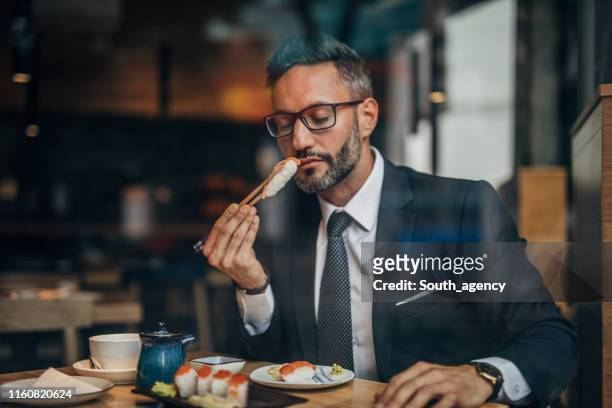 man eating sushi in the restaurant - sushi restaurant stock pictures, royalty-free photos & images